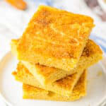 A stack of snickerdoodle blondies with crackly cinnamon sugar tops on white plates.