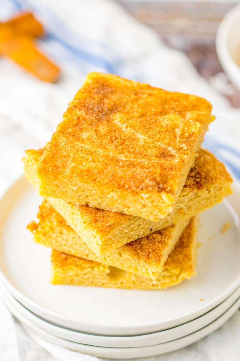 A stack of snickerdoodle blondies with crackly cinnamon sugar tops on white plates.
