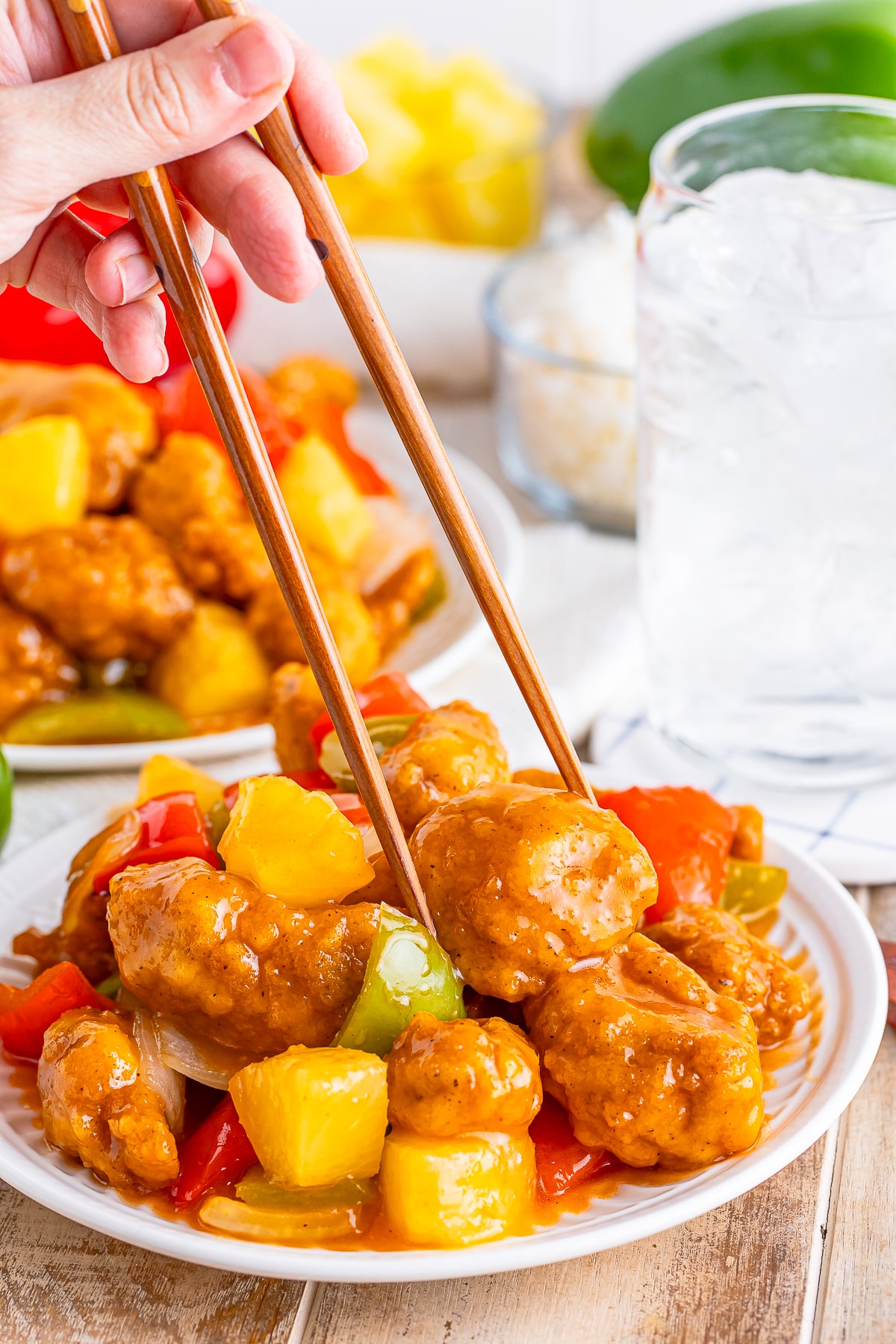 a hand grabbing a piece of Hong Kong Style Sweet and Sour Chicken on a plate