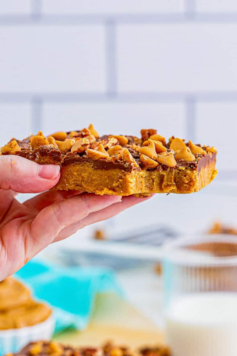 A stack of no-bake peanut butter bars with a chocolate layer and toffee and pecan topping.