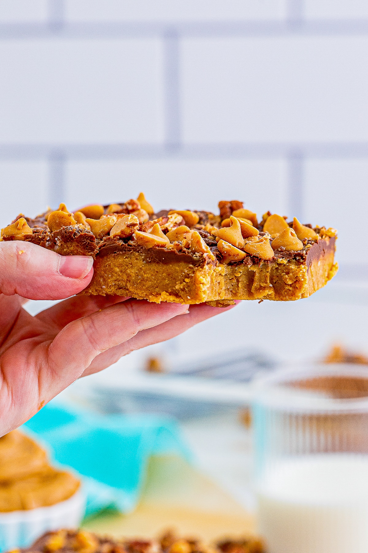 a hand holding up No-Bake Peanut Butter Bars in air with a bite taken out