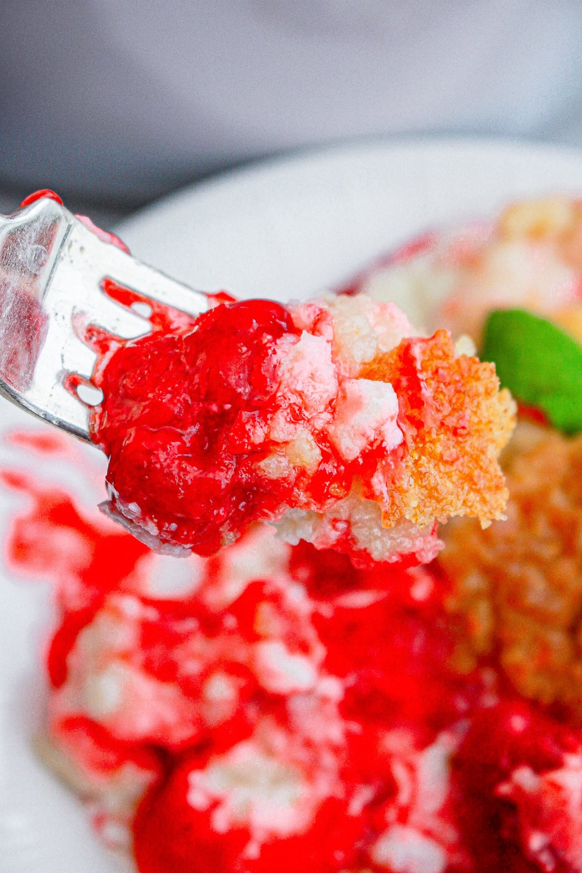 a fork holding up a bite of Strawberry Dump Cake in air
