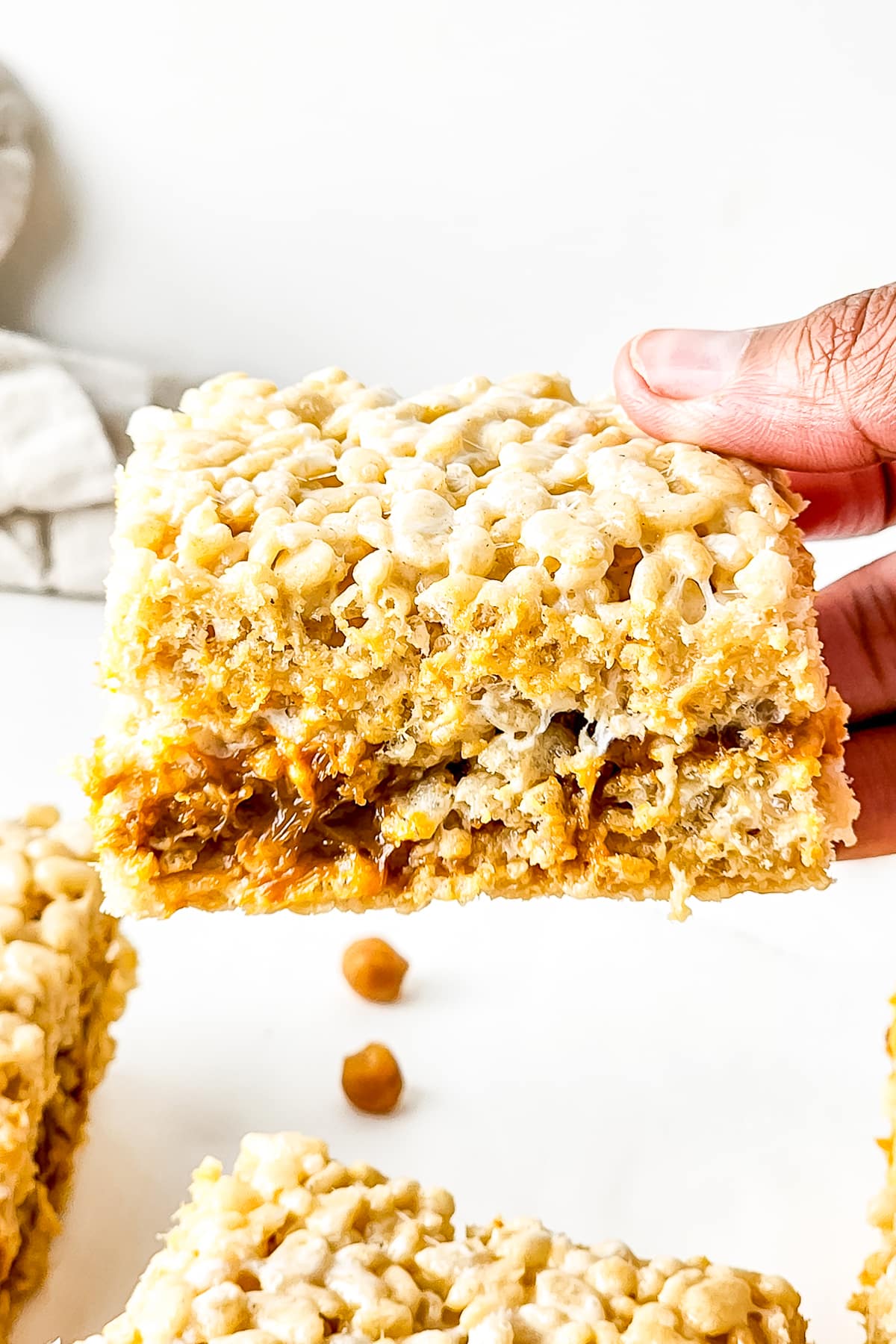 a hand holding up Brown Butter Rice Crispy Treats in air