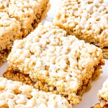 A stack of caramel rice krispie treats showing the dulce de leche layer through the middle.