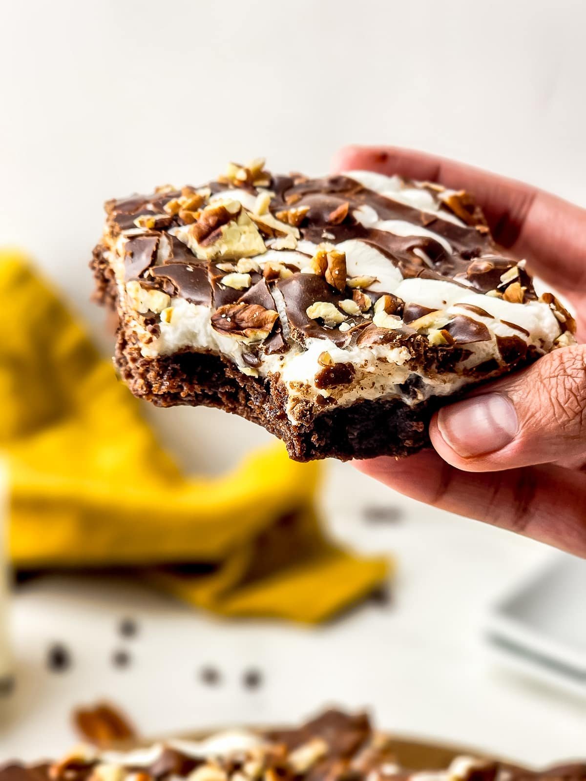 a hand holding up Brownie Bars with a bite taken out in air