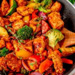A skillet of one pan chicken and vegetables with juicy chicken, bell peppers, broccoli, and zucchini.