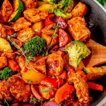 A skillet of one pan chicken and vegetables with juicy chicken, bell peppers, broccoli, and zucchini.