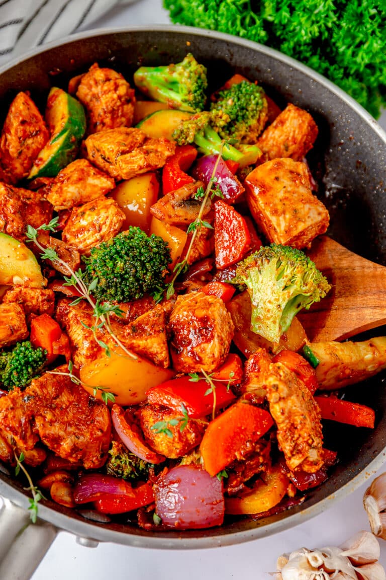 A skillet of one pan chicken and vegetables with juicy chicken, bell peppers, broccoli, and zucchini.