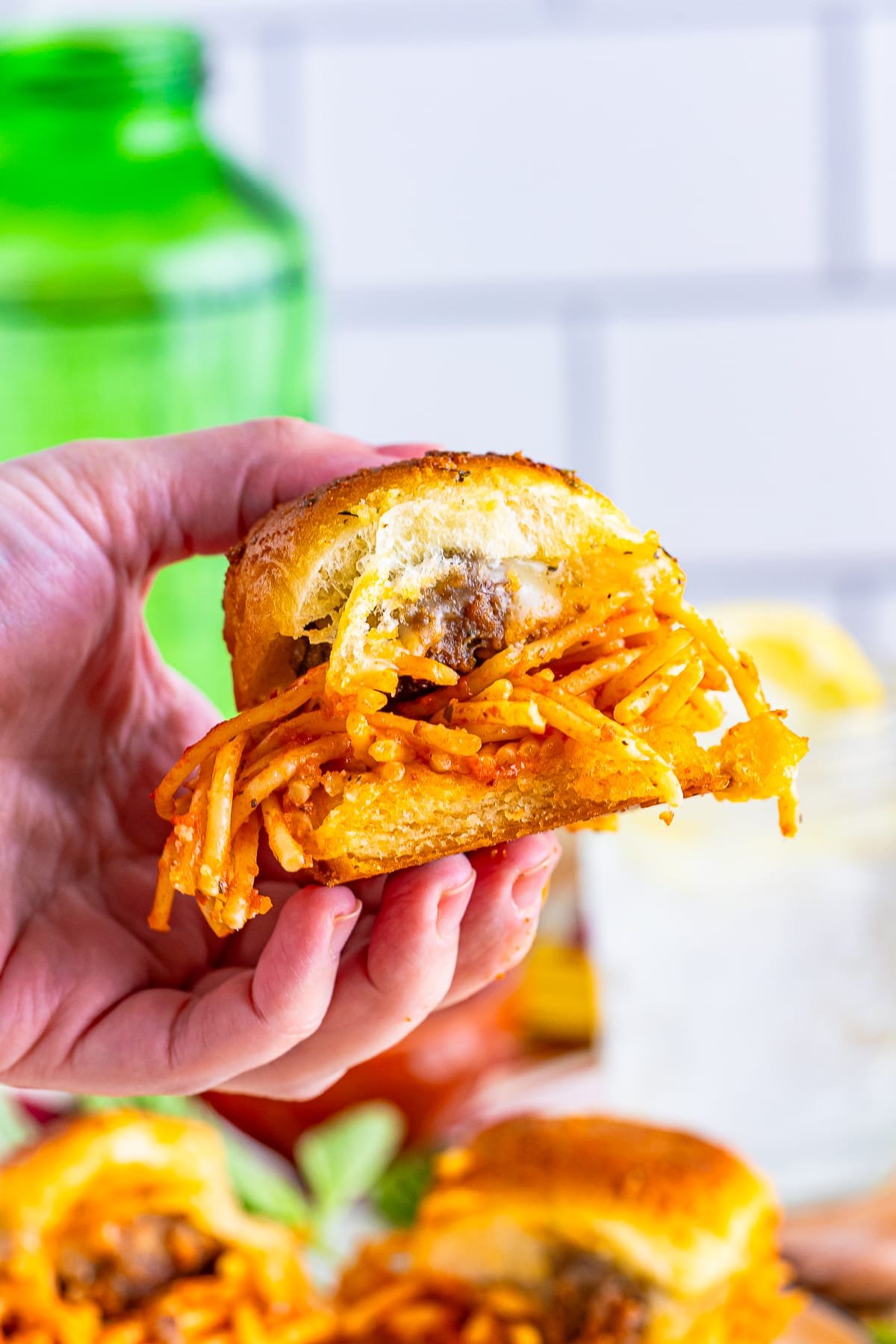 a hand holding up Meatball Sliders in air