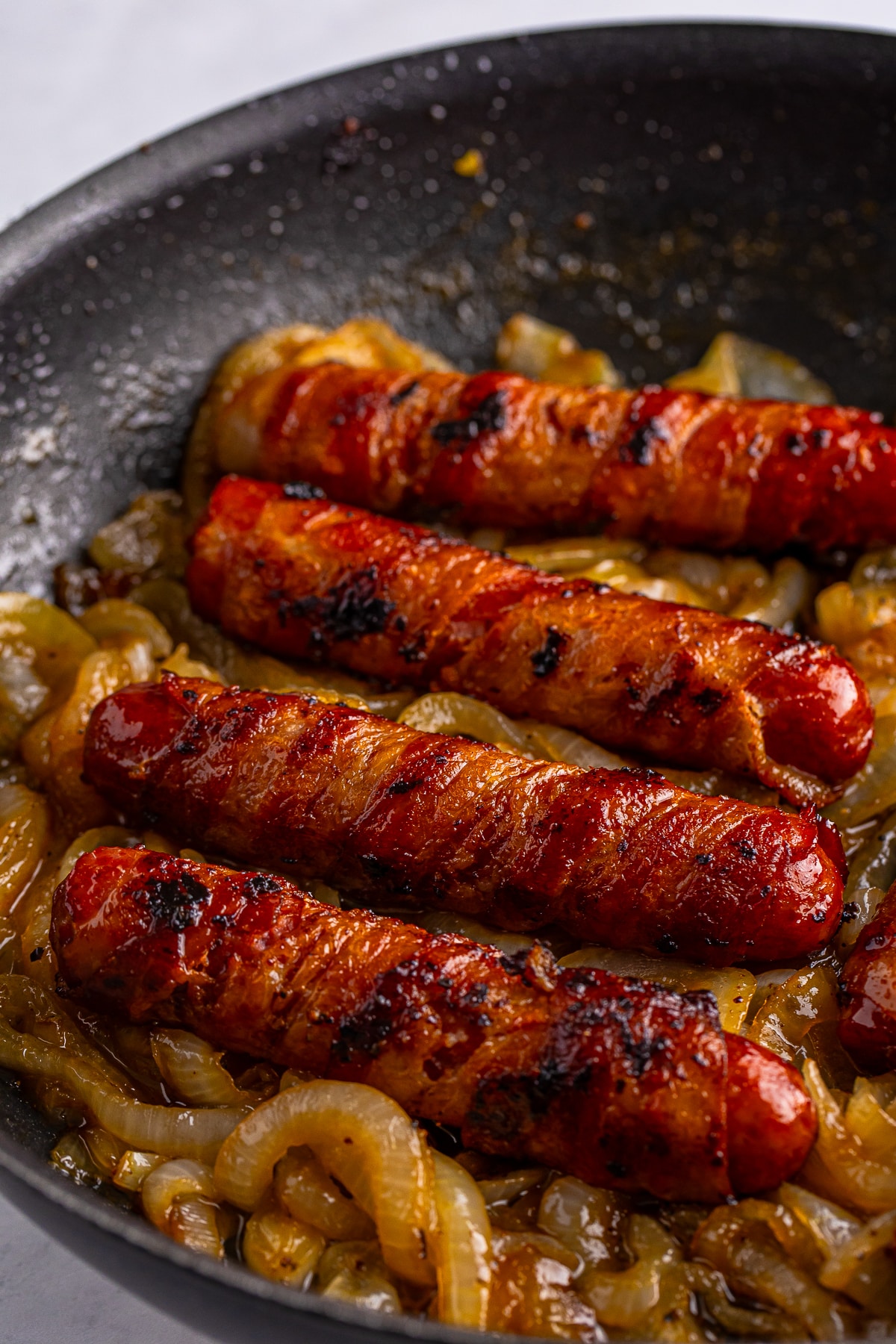 cooked Bratwurst Sausage with caramelized onions in pan