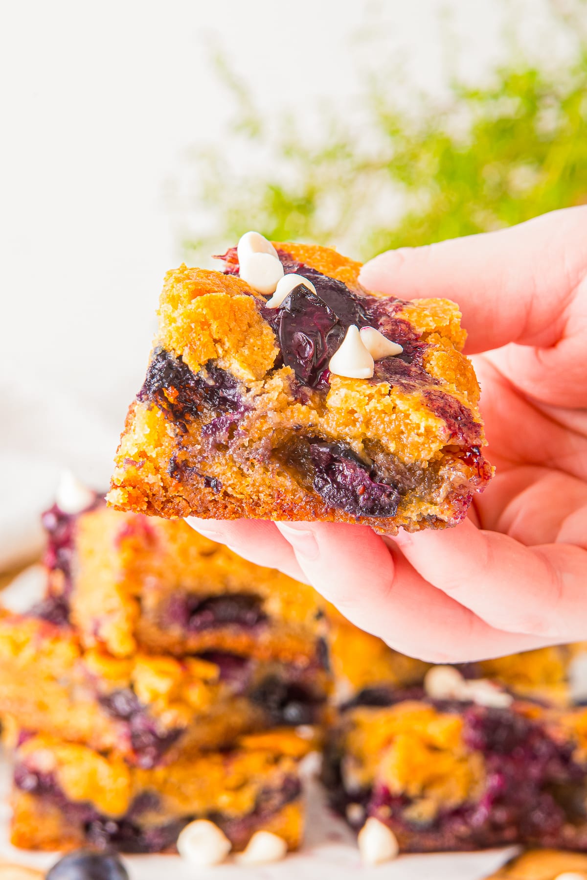 a hand holding up White Chocolate Blondies in air