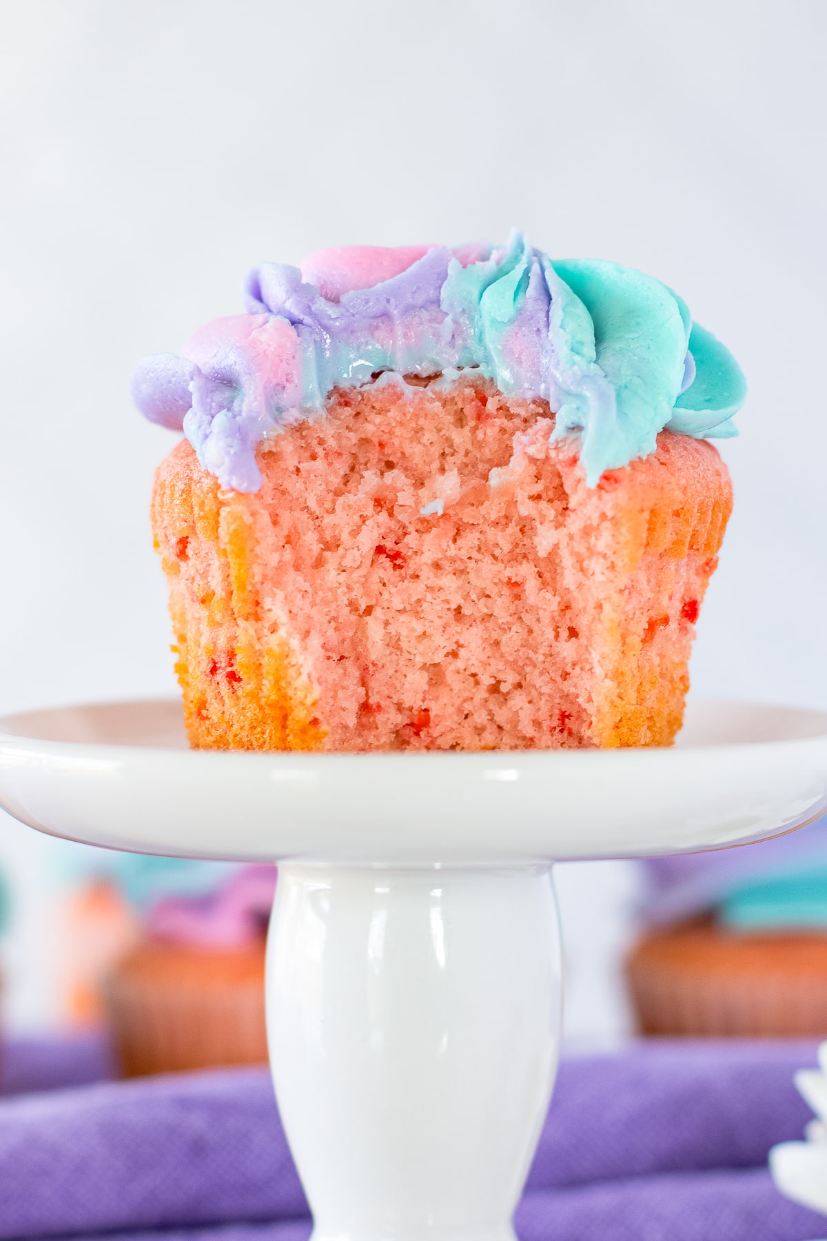 Cherry Cupcakes with a bite taken out on a cake stand