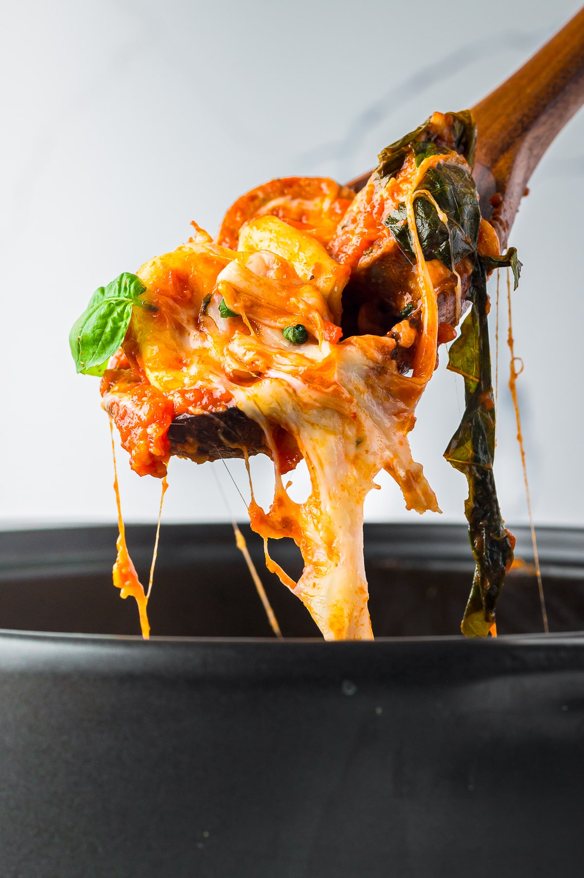 a spoon holding up a portion of Baked Tortellini in the air with cheesy pull