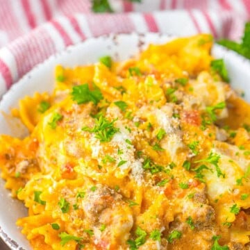 A bowl of one pot lasagna with bowtie pasta, melted cheese, and parsley.