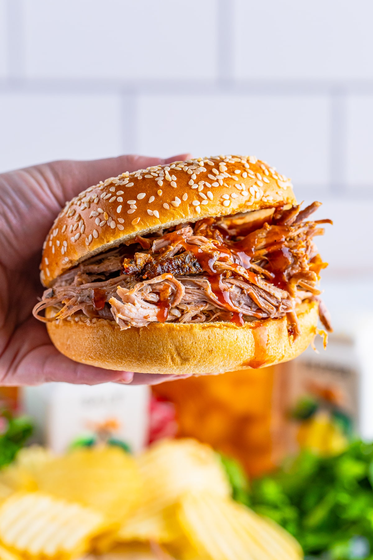 a hand holding up an Oven Baked Pulled Pork sandwich in air