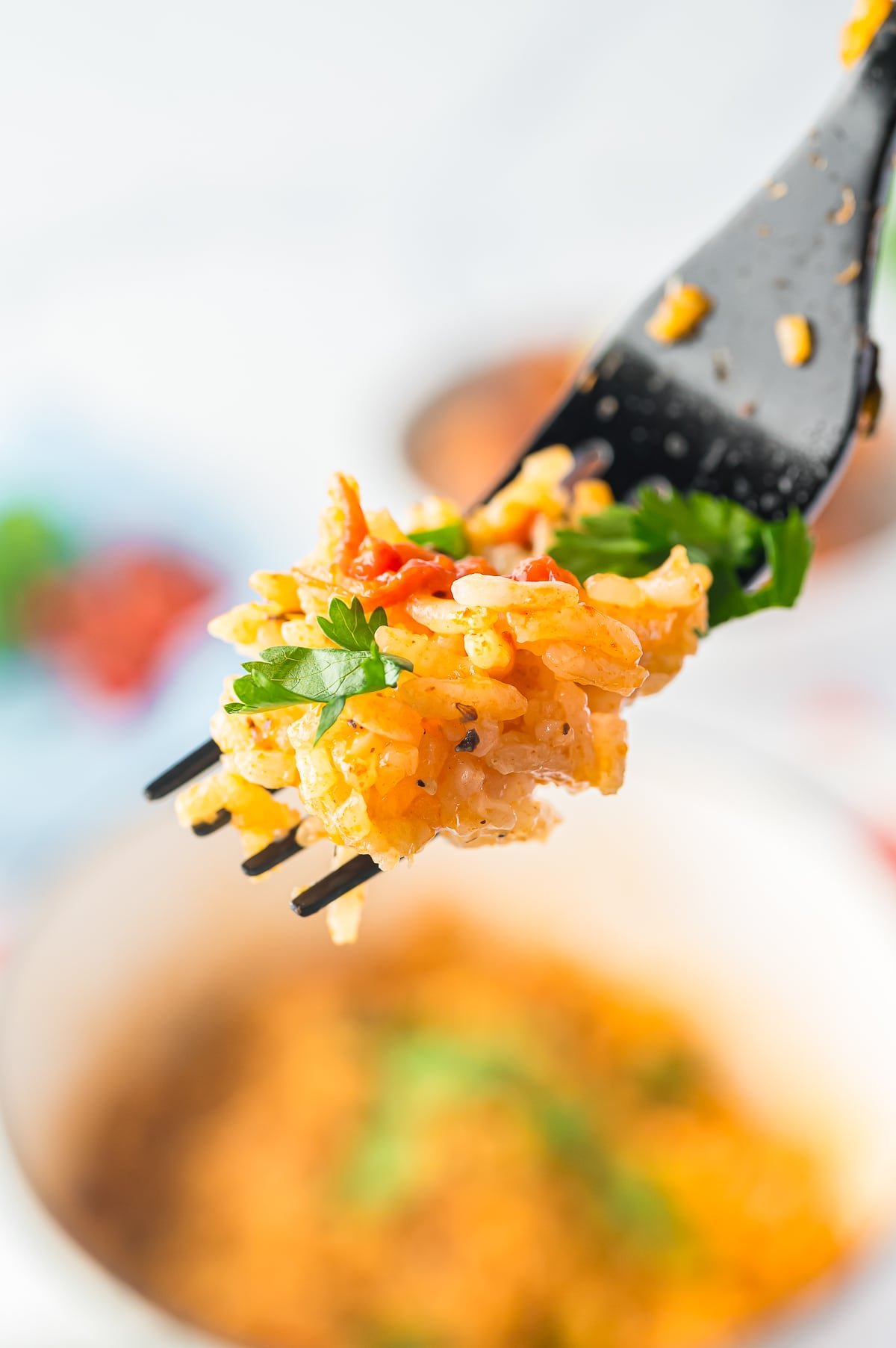 a fork holding up a bite of Easy Spanish Rice recipe in air