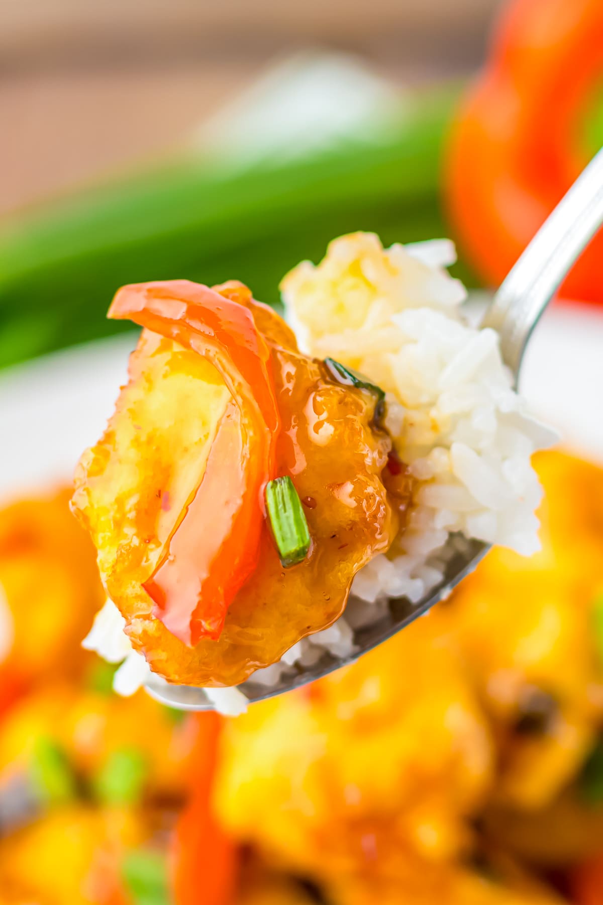 a spoon holding up a bite of Sweet Chili Sauce Chicken in air