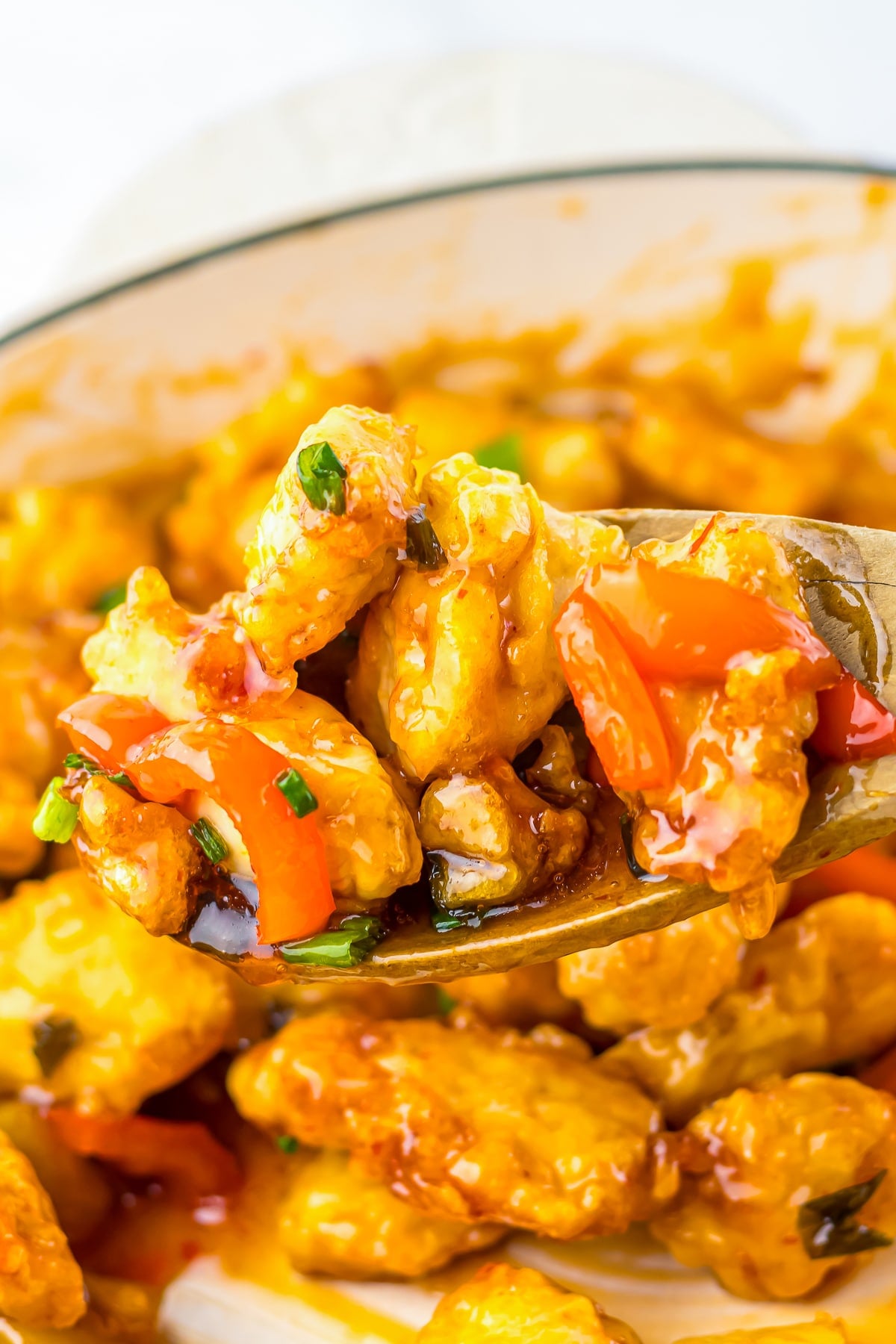 a spoon holding up Sweet Chili Sauce Chicken over the skillet