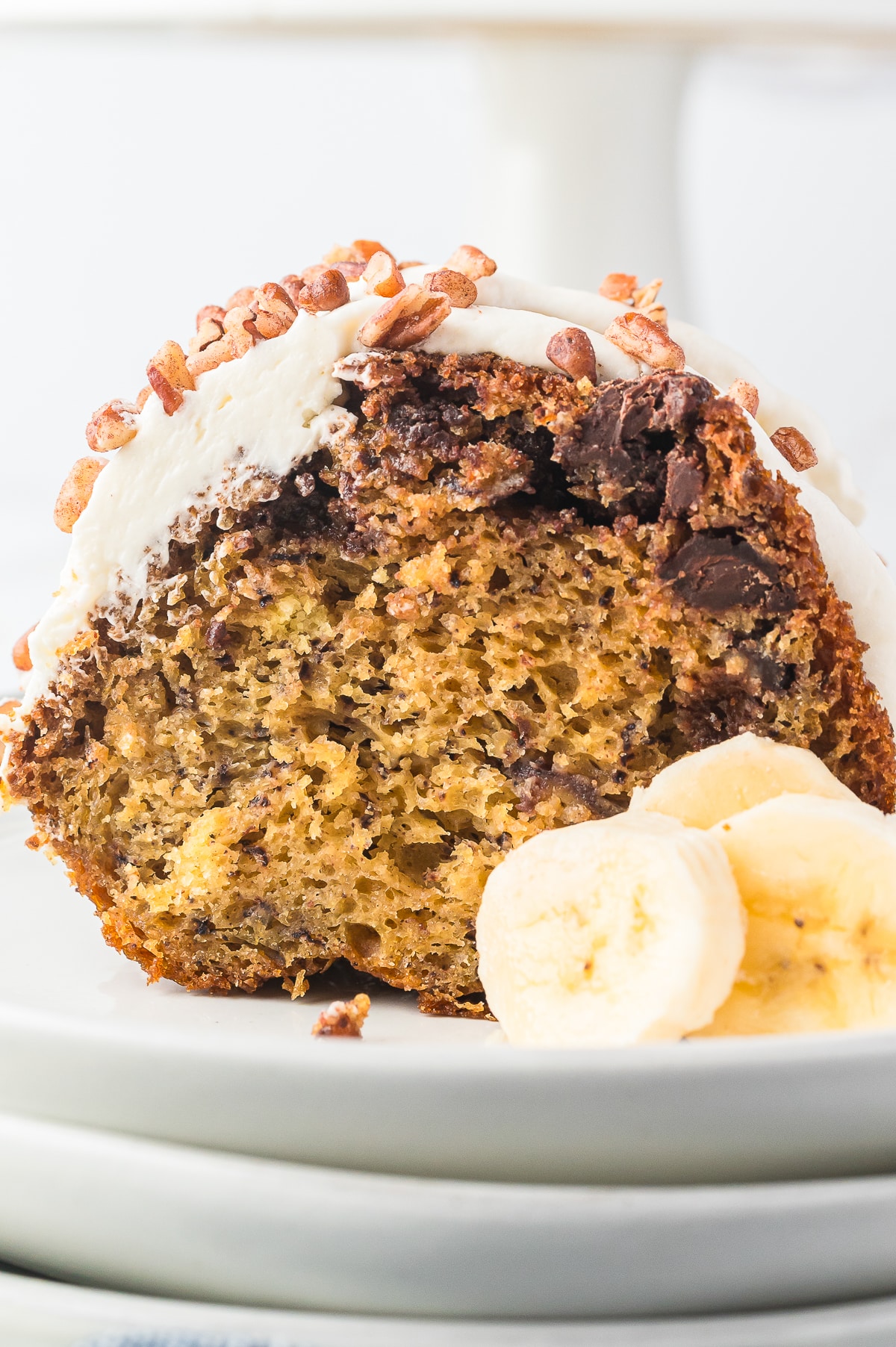 a slice of Banana Bundt Cake on white plate with banana slices