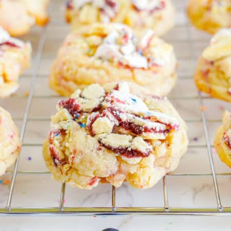 Blueberry pop tart sugar cookies on a wire rack topped with crushed Pop-Tarts and sprinkles.