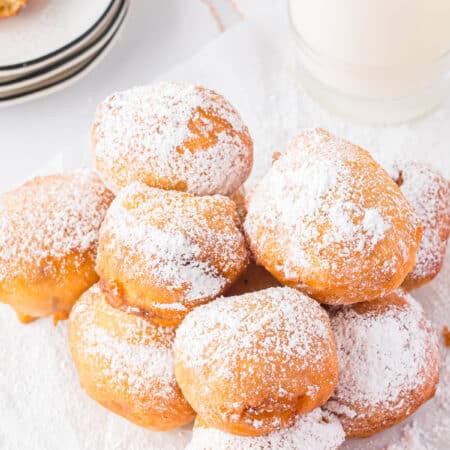 A plate of golden deep fried Twinkie bites dusted with powdered sugar.