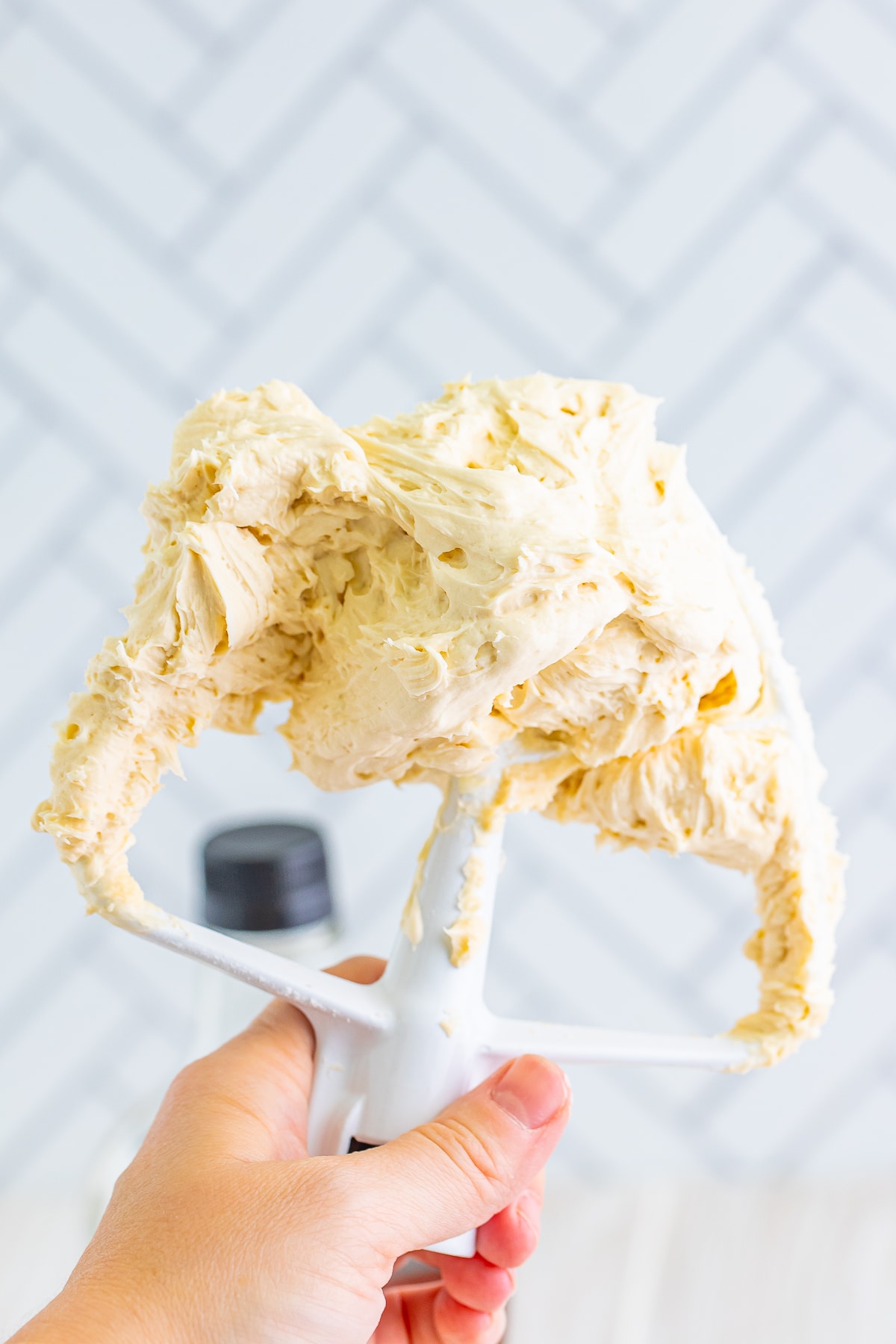 maple frosting on a paddle hook attachment, a hand holding it up in air