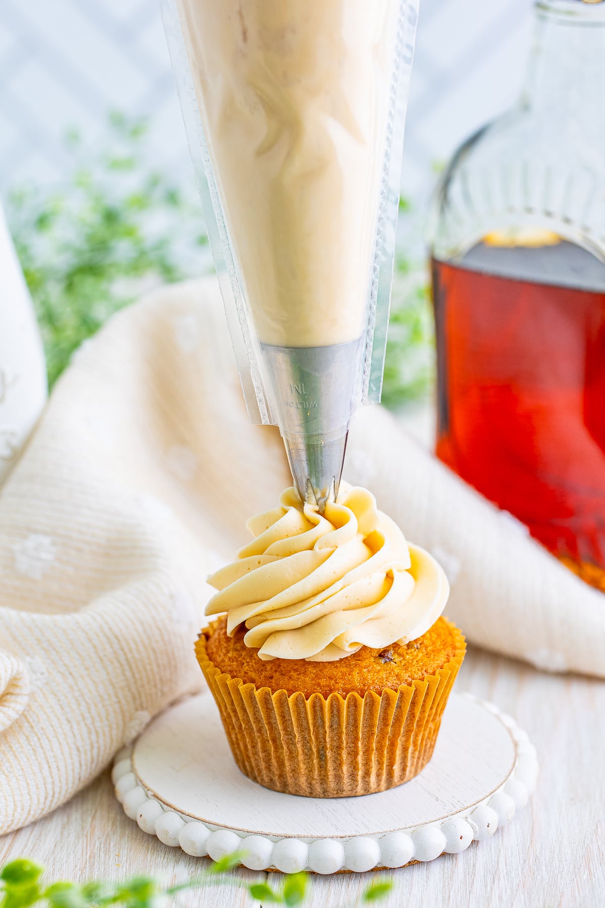 a piping bag piping maple frosting on to a cupcake