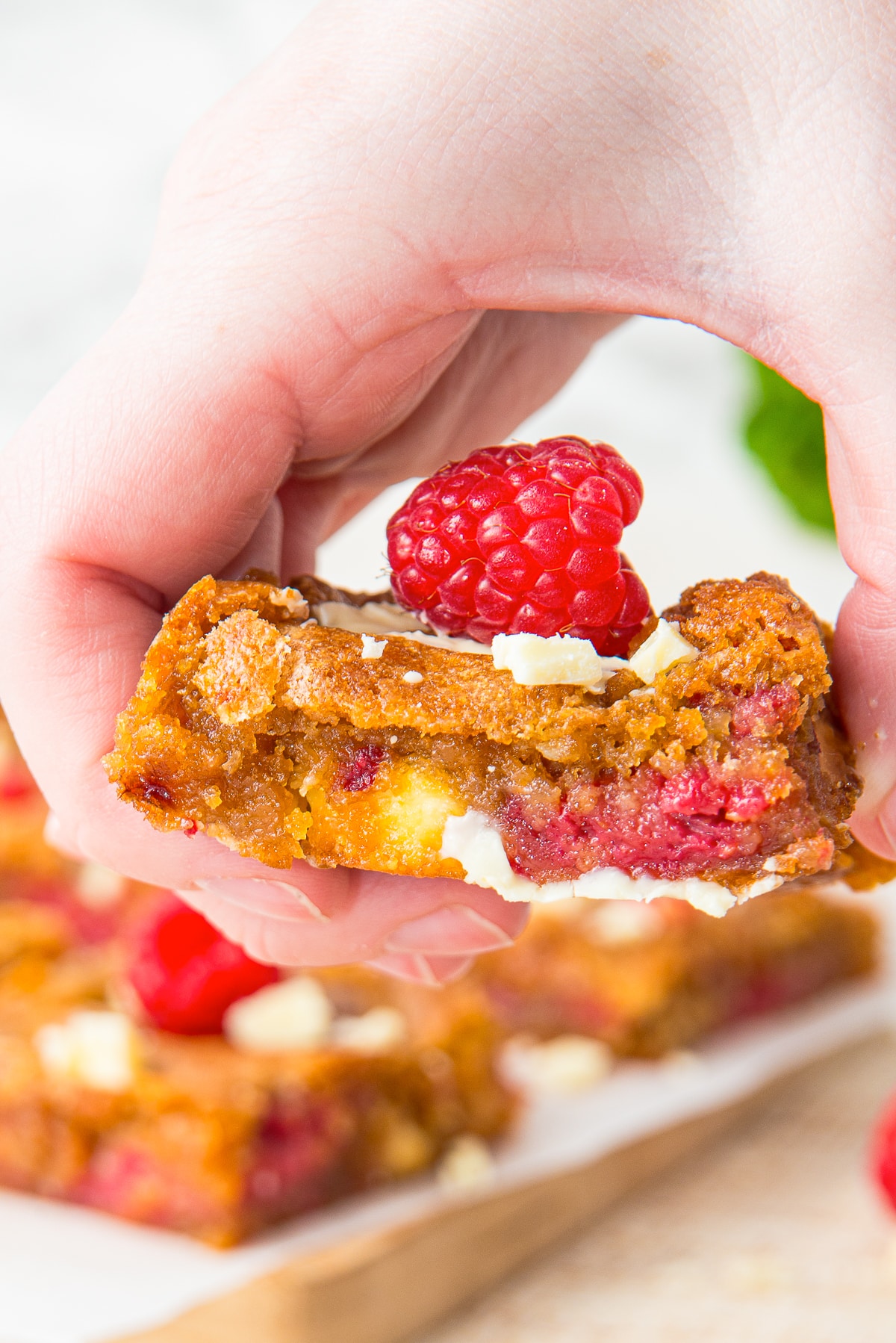 a hand holding up Raspberry White Chocolate Brownies in air