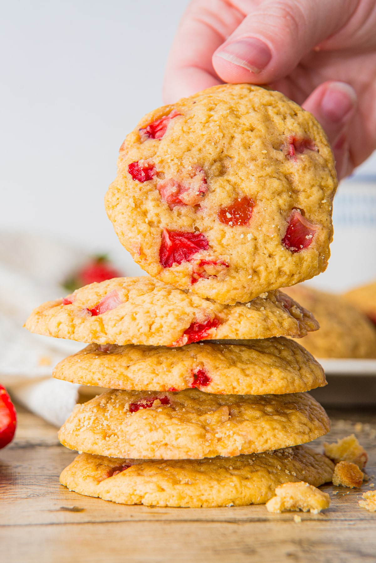 a hand picking up Strawberry Cookies from a stack