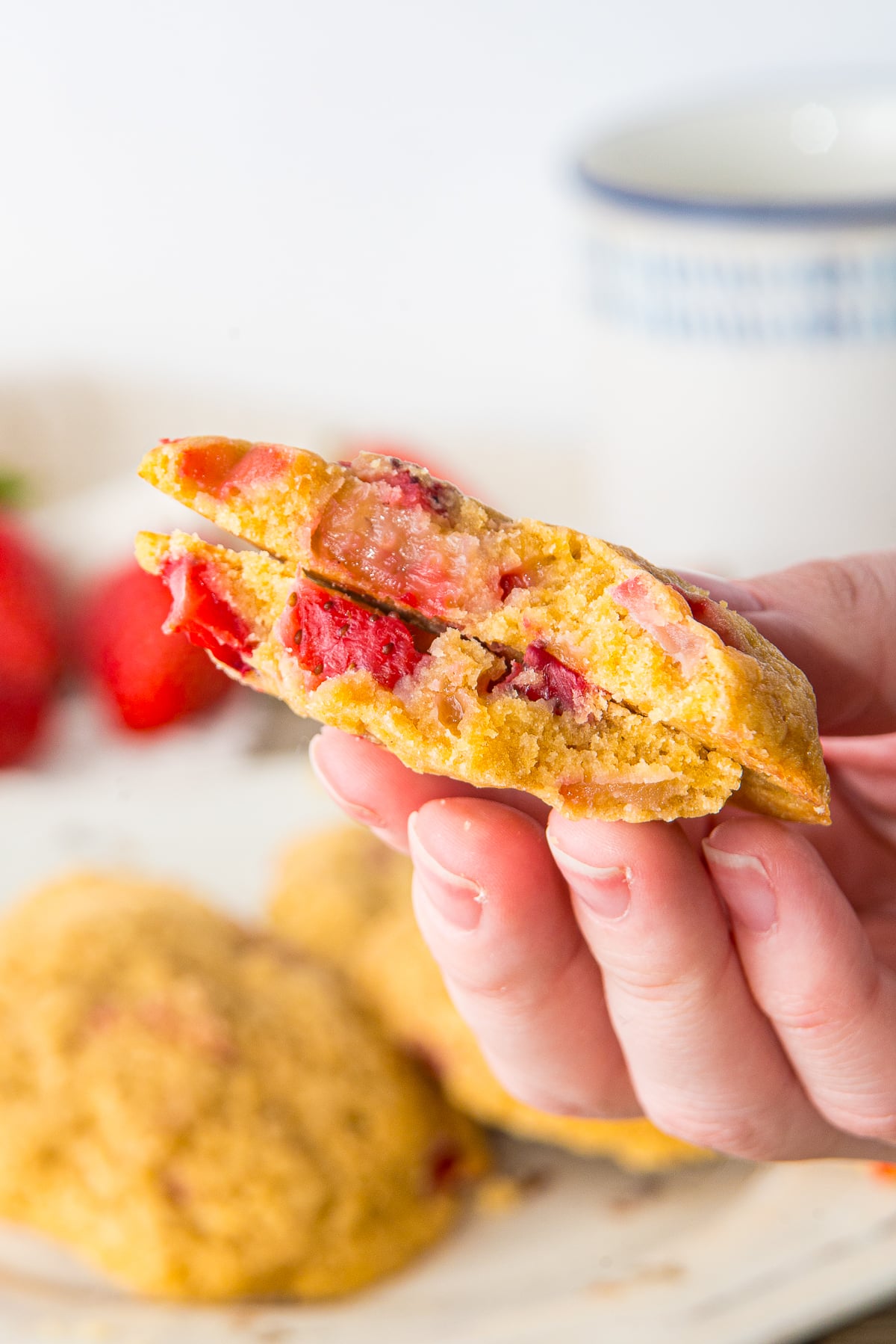 a hand holding up Strawberry Cookies in air to see the interior