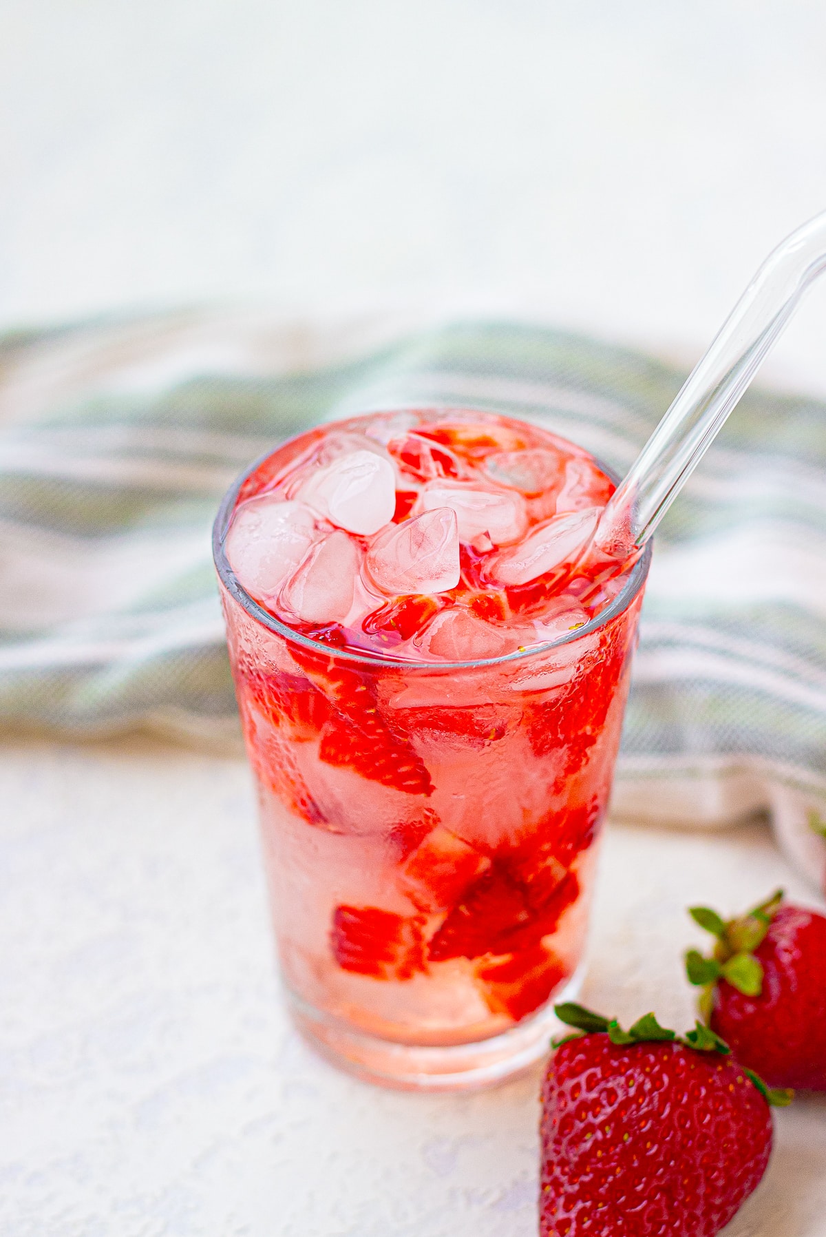 Strawberry Acai Refresher on a white table top and glass straw