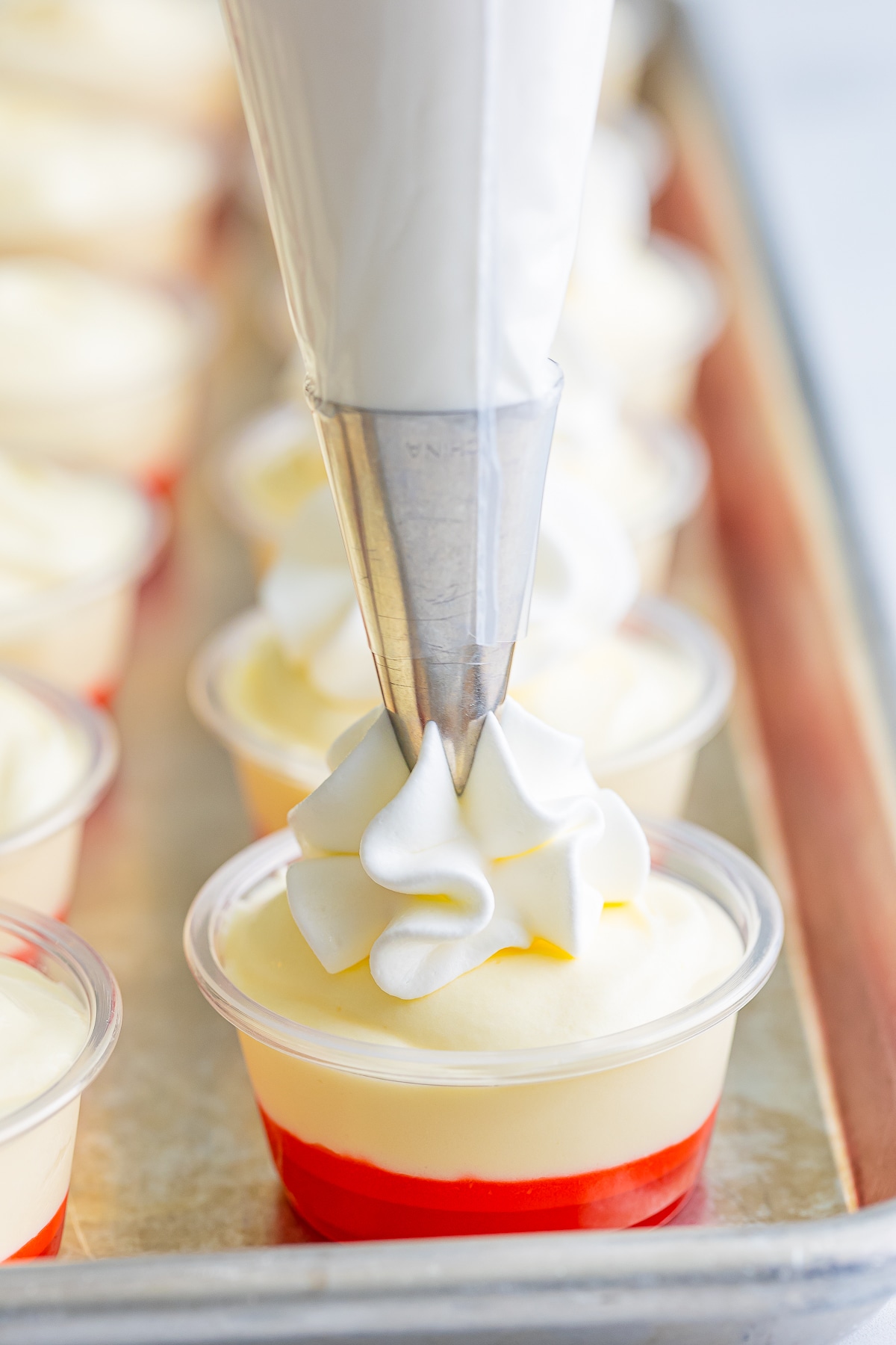whipped topping being piped on banana pudding shots