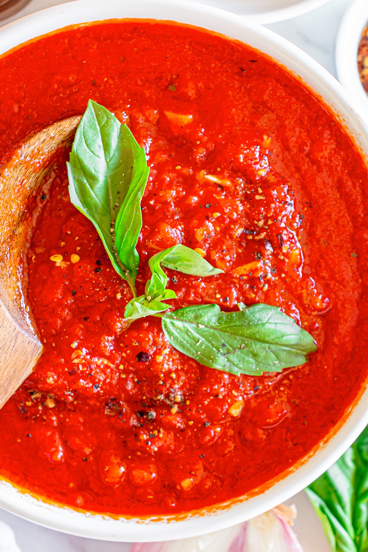 overhead image of homemade marinara sauce in a bowl with garnishes
