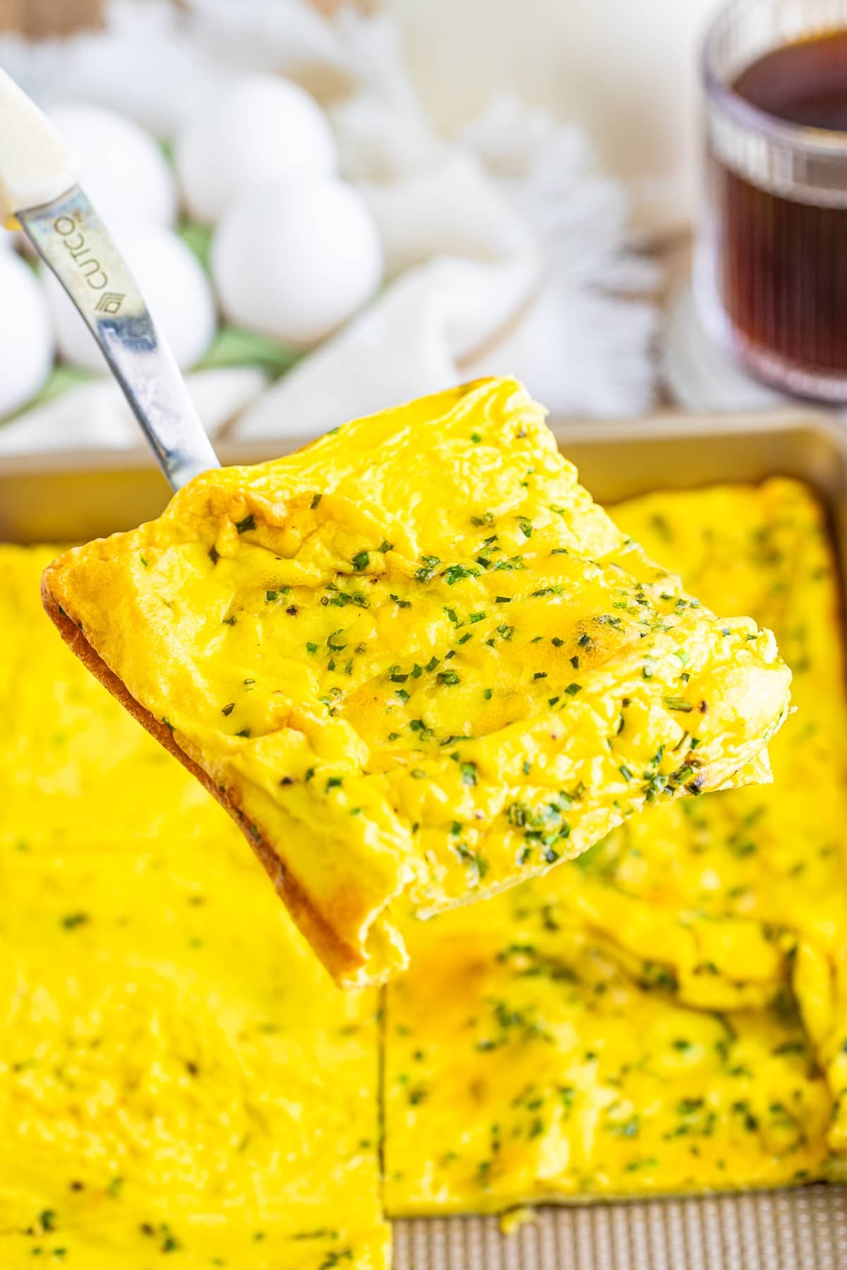 a spatula holding up a piece of sheet pan omelet in air