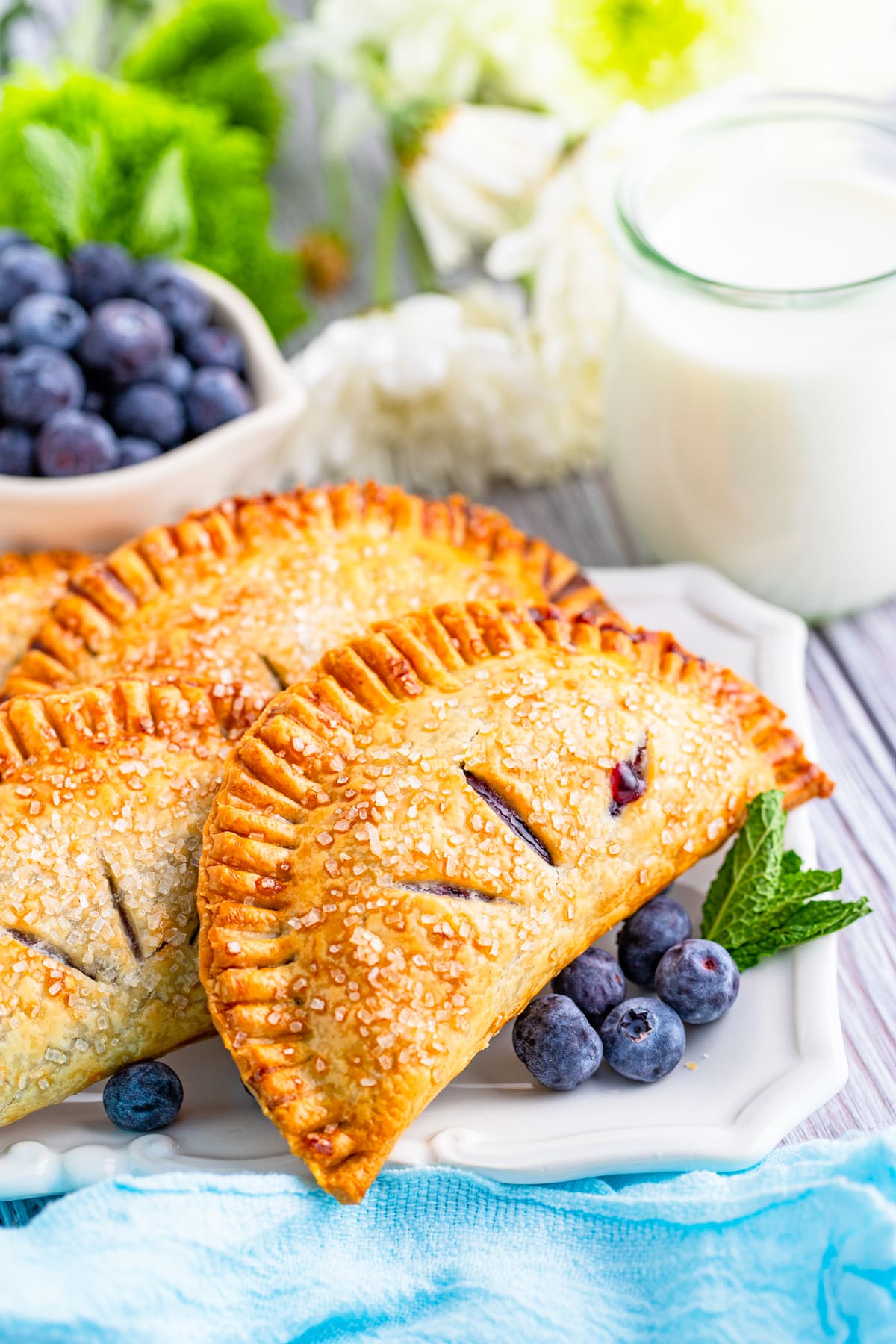 blueberry Hand Pies on a square white plate with fresh berries and mint