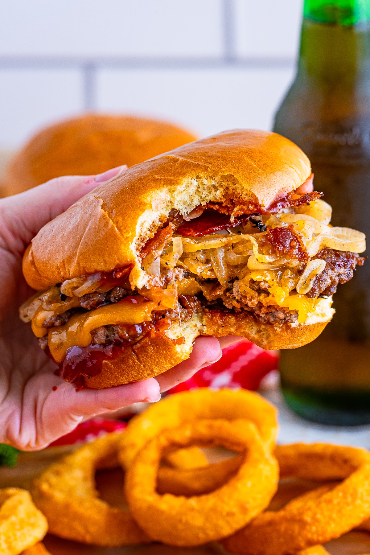 a hand holding up Blackstone Smash Burgers that has a bite taken out in air