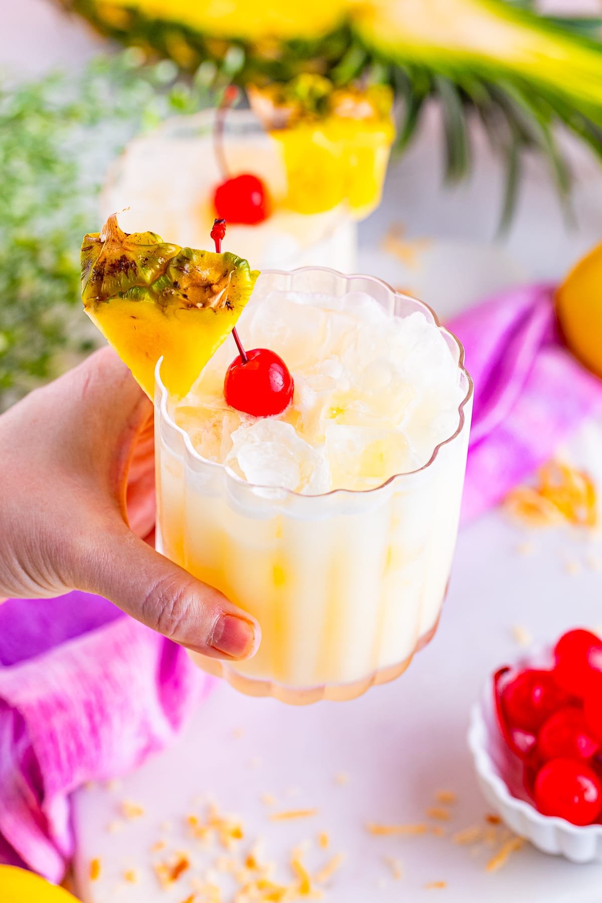 a hand holding up a glass of Pineapple Lemonade in air
