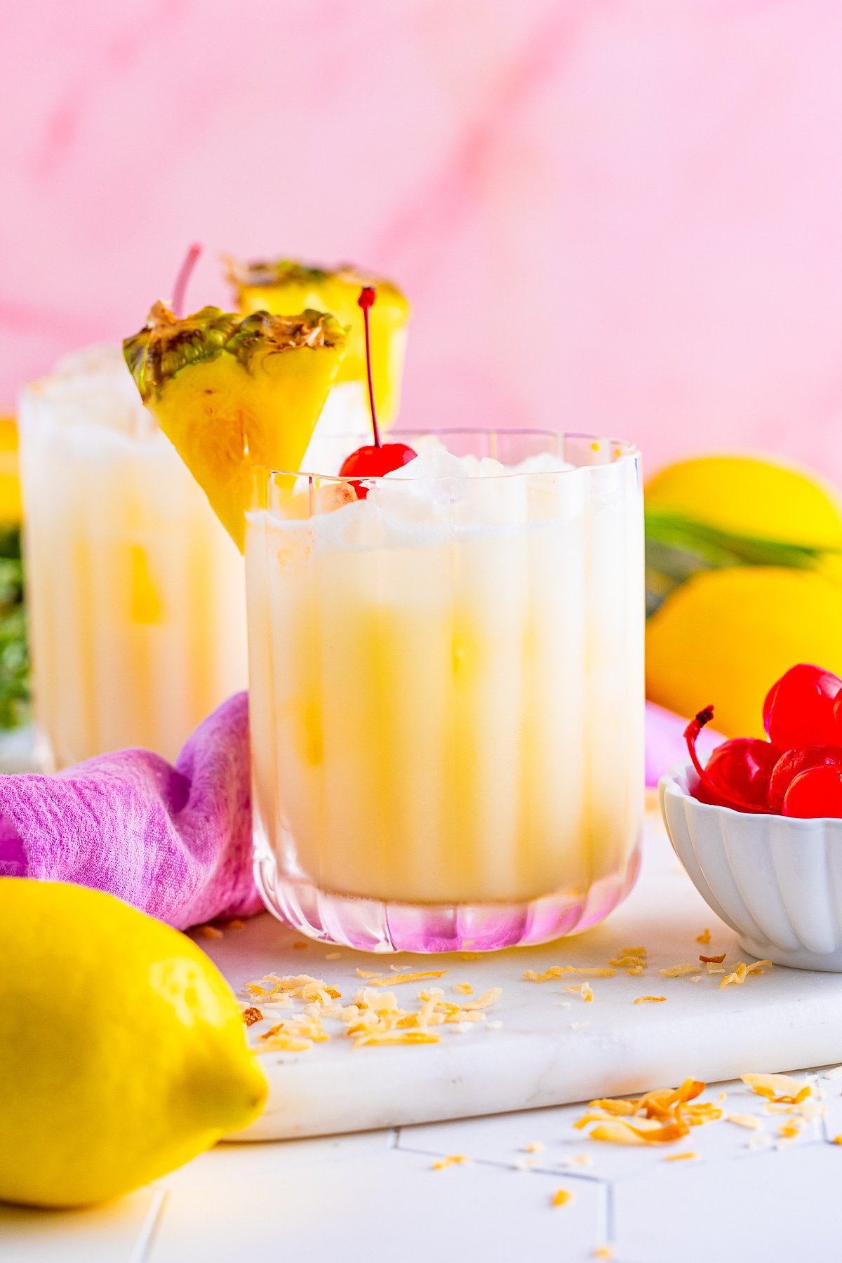 eye level photo of Pineapple Lemonade in serving glasses with pink background