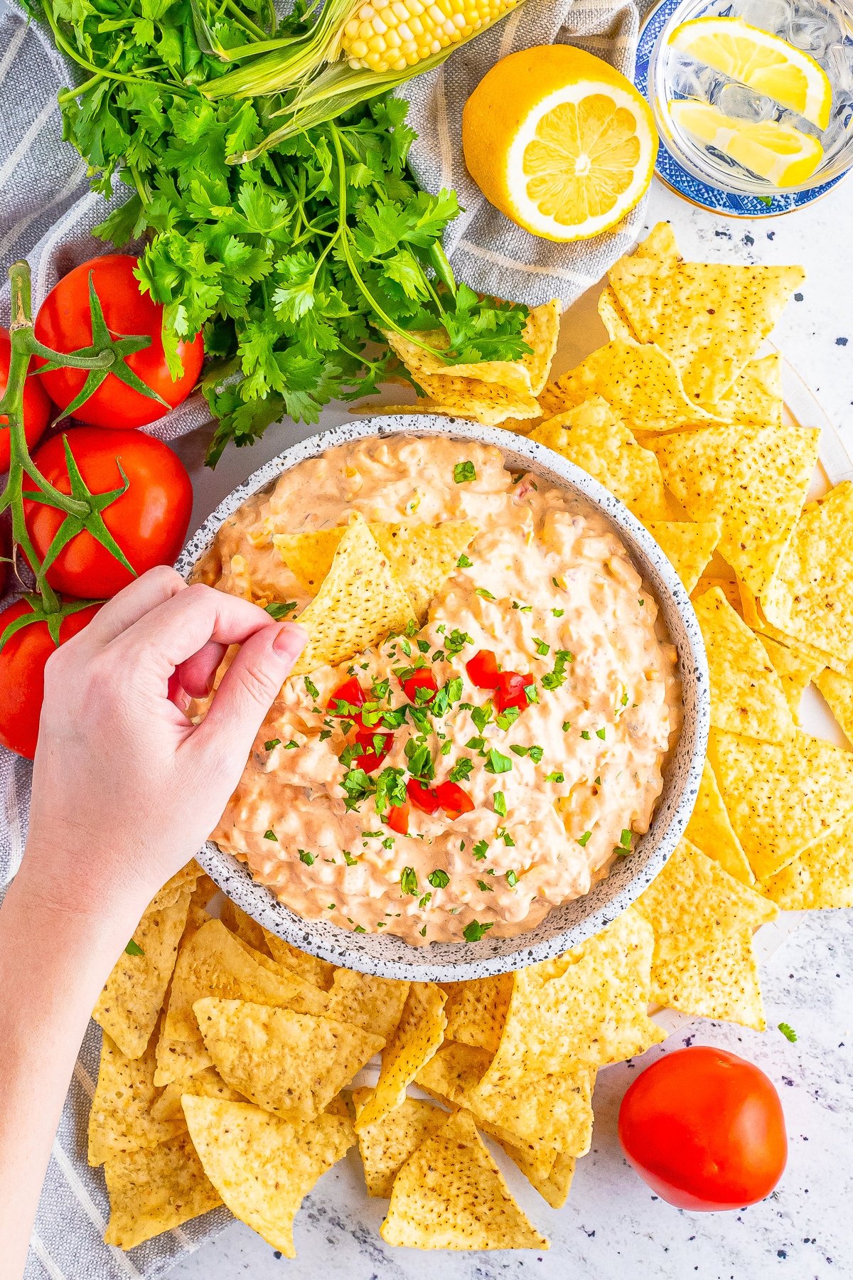 overhead image Cream Cheese Taco Dip in a bowl with a hand dipping into it with a chip