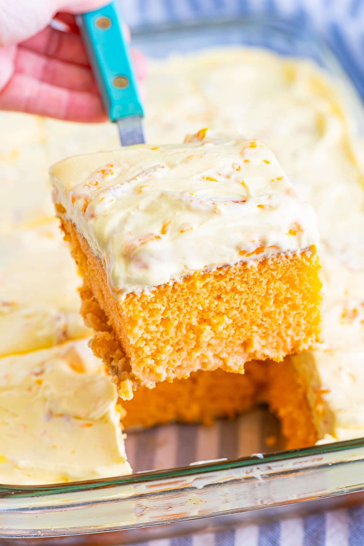a spatula holding up a slice of Orange Creamsicle Cake in air