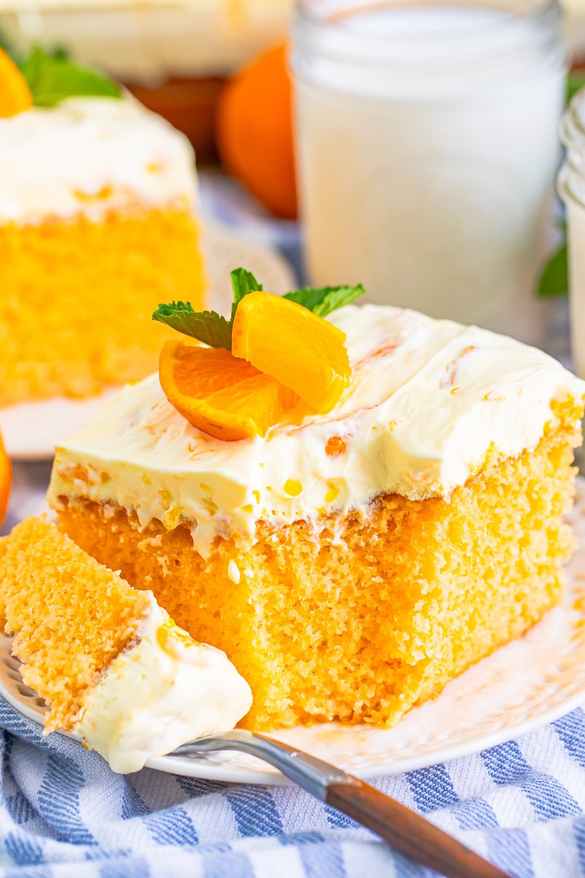 a slice of Orange Creamsicle Cake with a bite taken out on a white plate