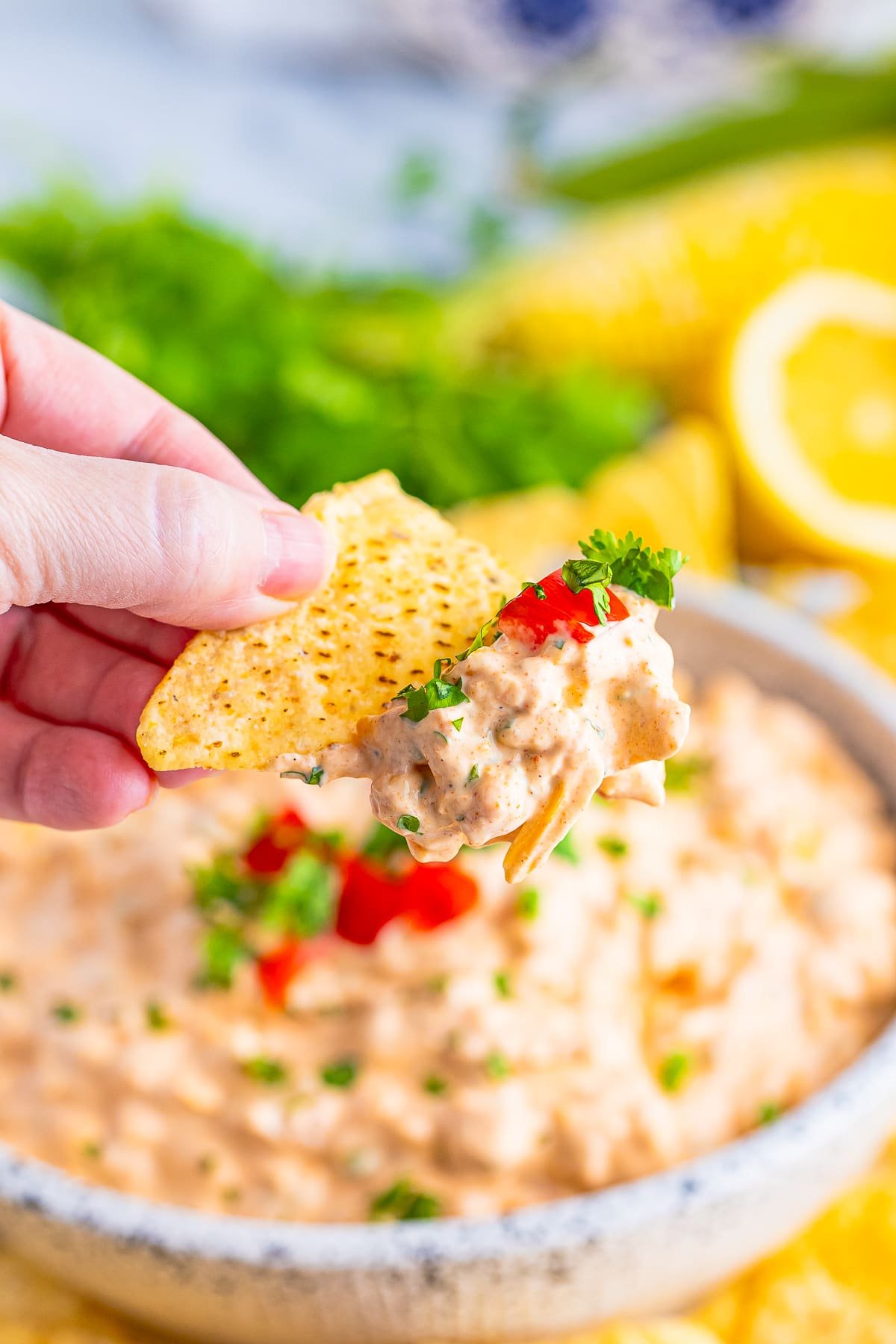 a hand holding up a chip in the air with Cream Cheese Taco Dip on it