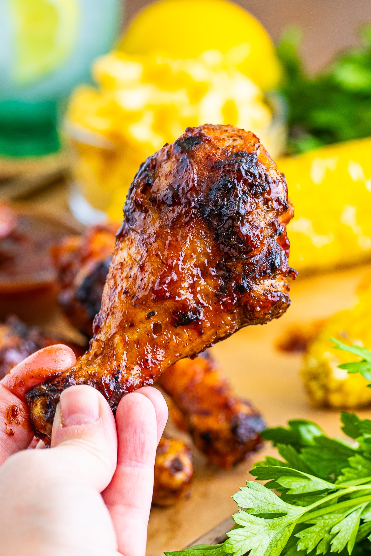 a hand holding up bbq Chicken Legs in air