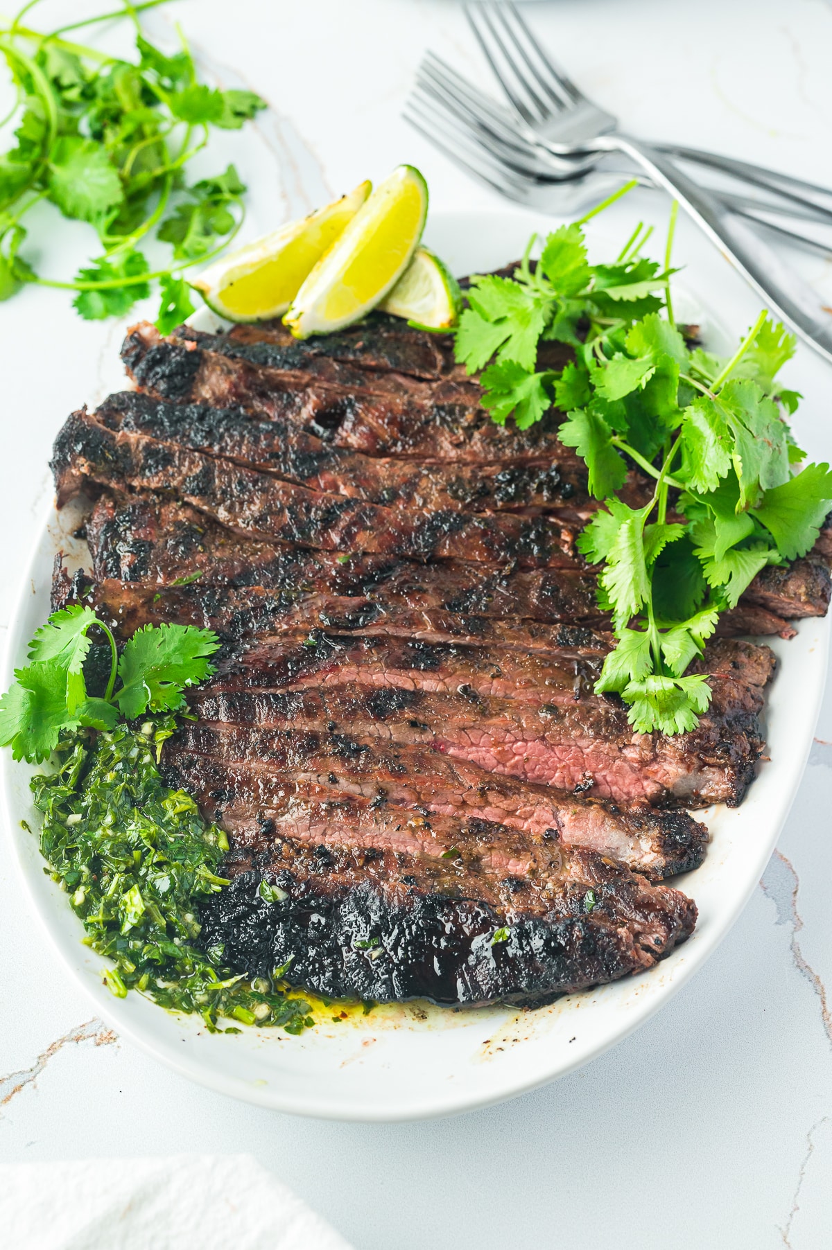 overhead image of grilled flank steak on a white platter