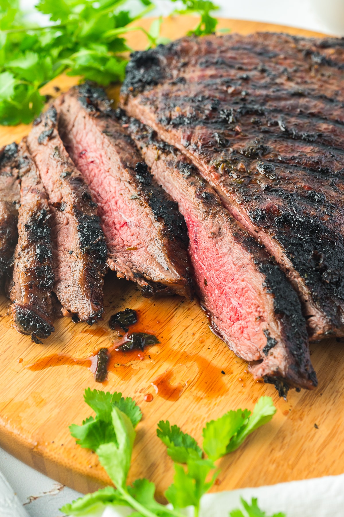 sliced grilled flank steak on a wooden serving board