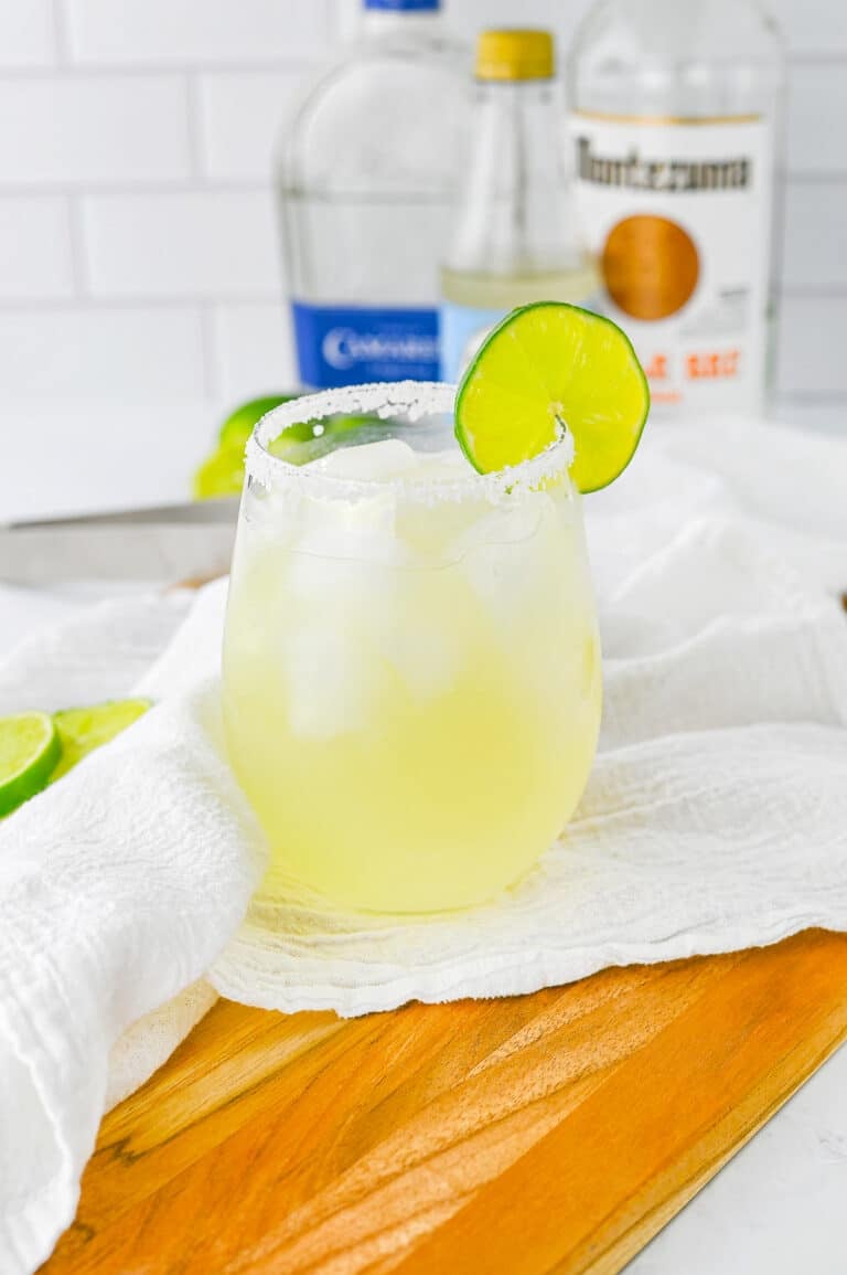 A classic margarita in a stemless glass with a salted rim and a fresh lime wheel