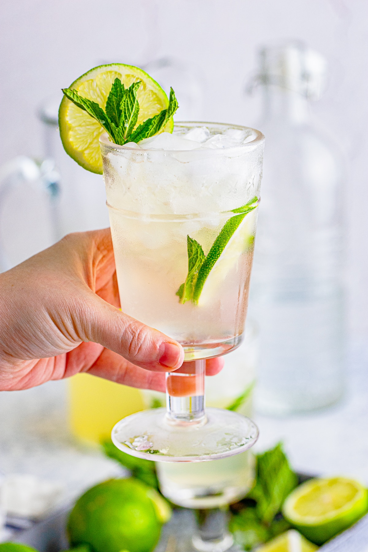 a hand holding up a glass filled with Mojitos Recipe in air