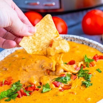 Creamy chorizo queso dip in a slow cooker topped with cilantro and served with tortilla chips.