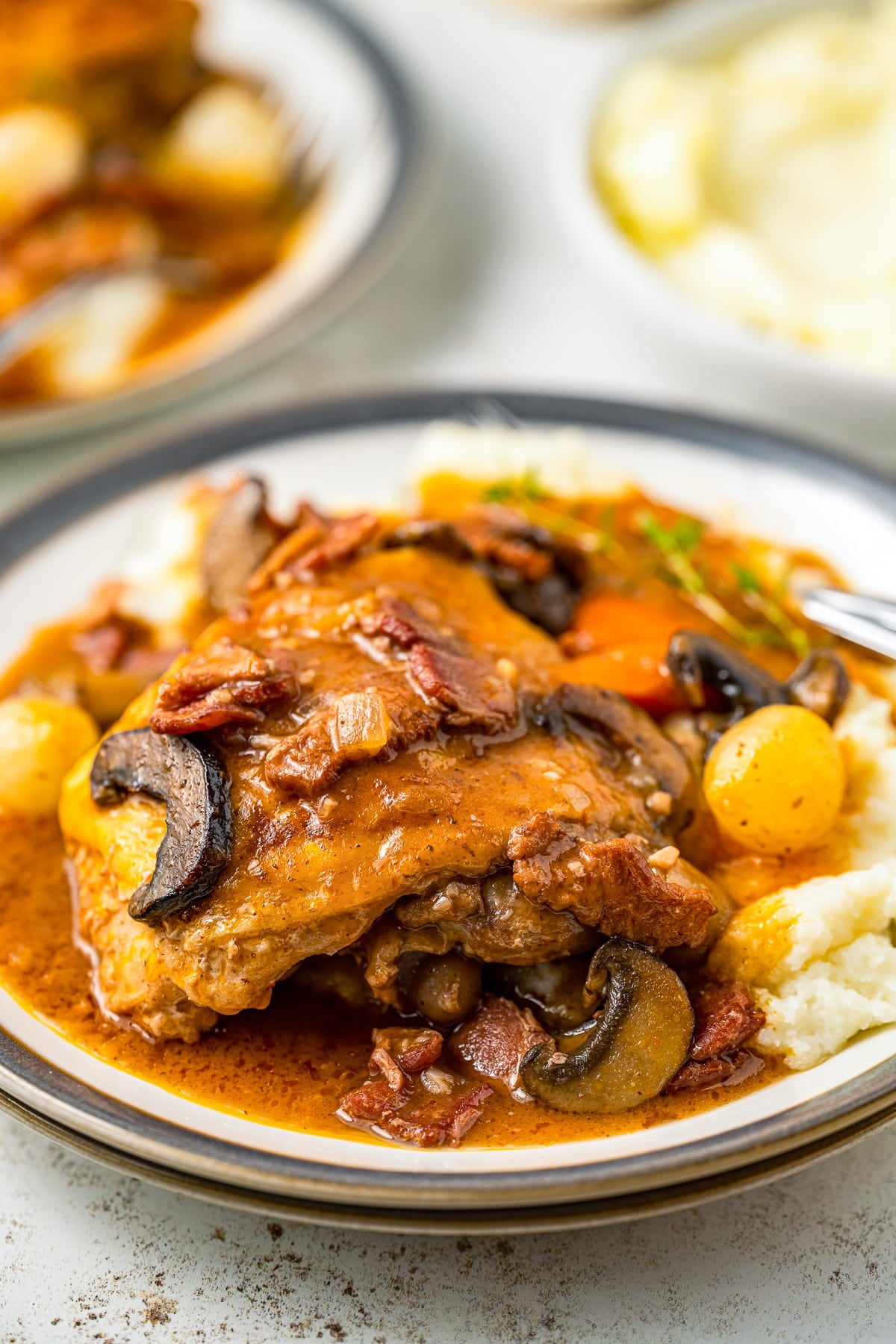 Coq au Vin Recipe served on a plate over mashed potatoes
