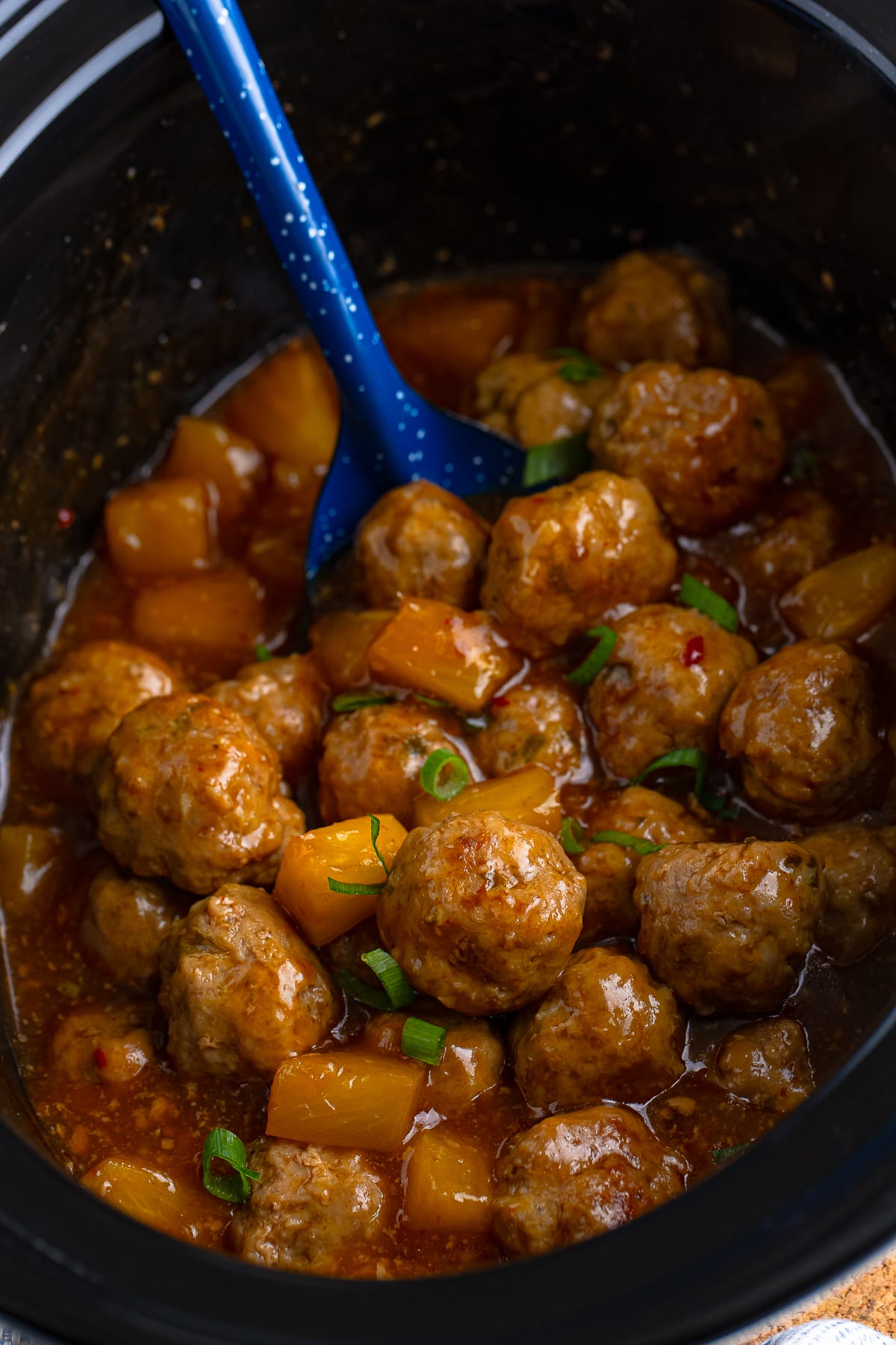 Pork Meatballs in slow cooker with blue spoon